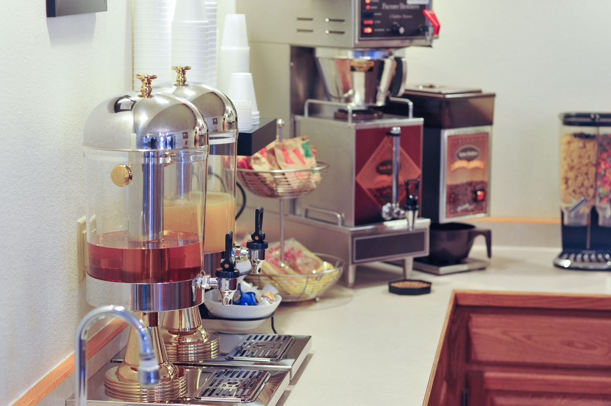 A coffee station with multiple coffee machines, a water dispenser, and a coffee cup holder.
