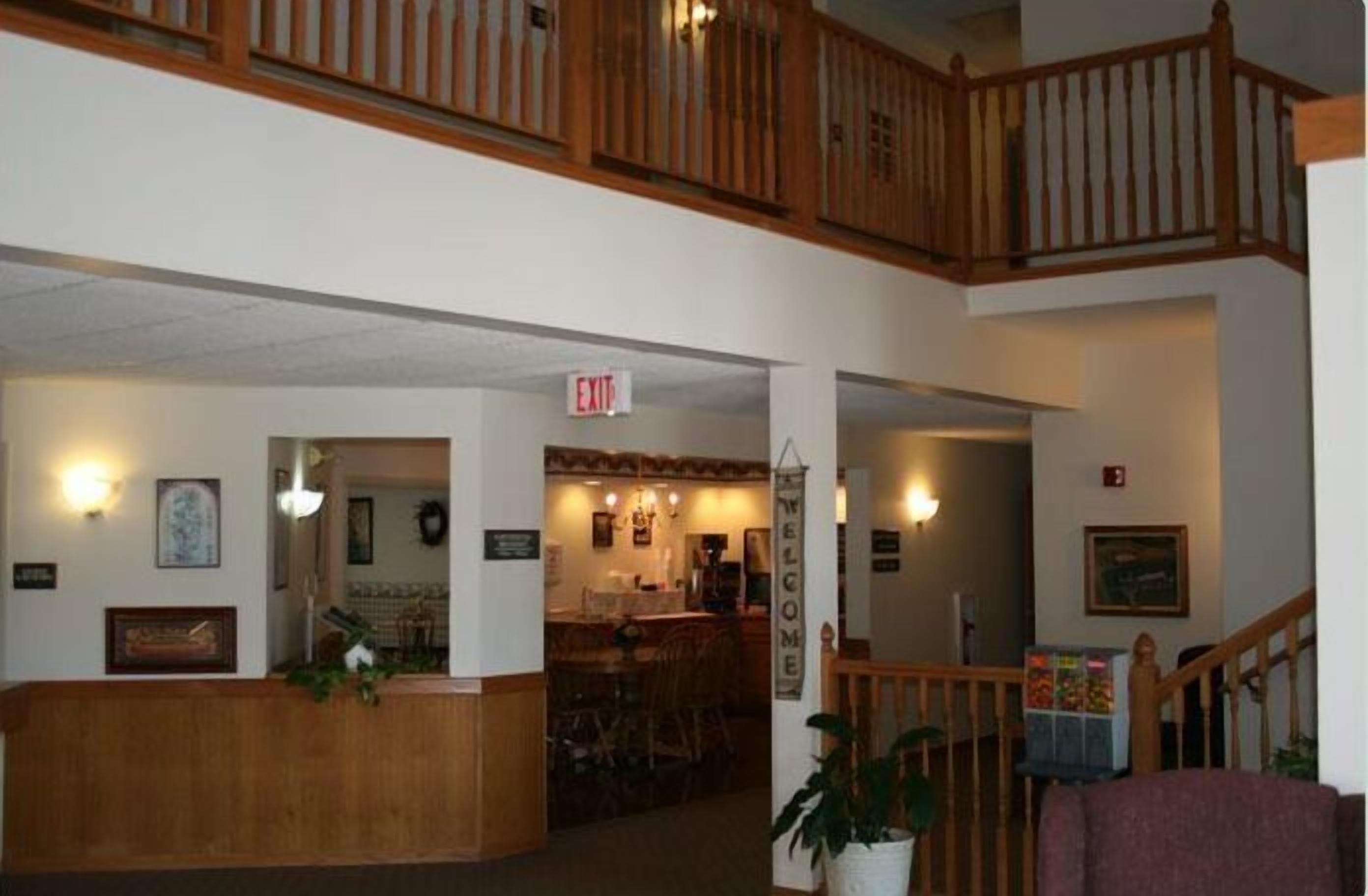 A hotel lobby with a reception desk, a staircase, and a bar area.