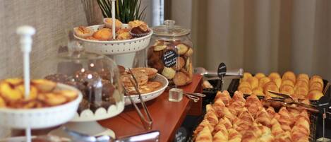 Una mesa de buffet con diversas opciones de panadería, incluyendo pasteles, muffins y pan.
