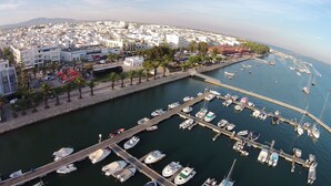 A marina with numerous boats docked, a cityscape in the background, and a clear view of the water. - Real Marina Residence (Olhao)