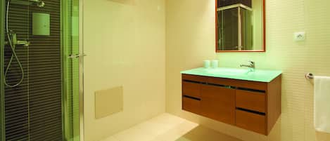 A modern bathroom with a glass-enclosed shower, a wooden vanity with a green countertop, and a large mirror above the sink.