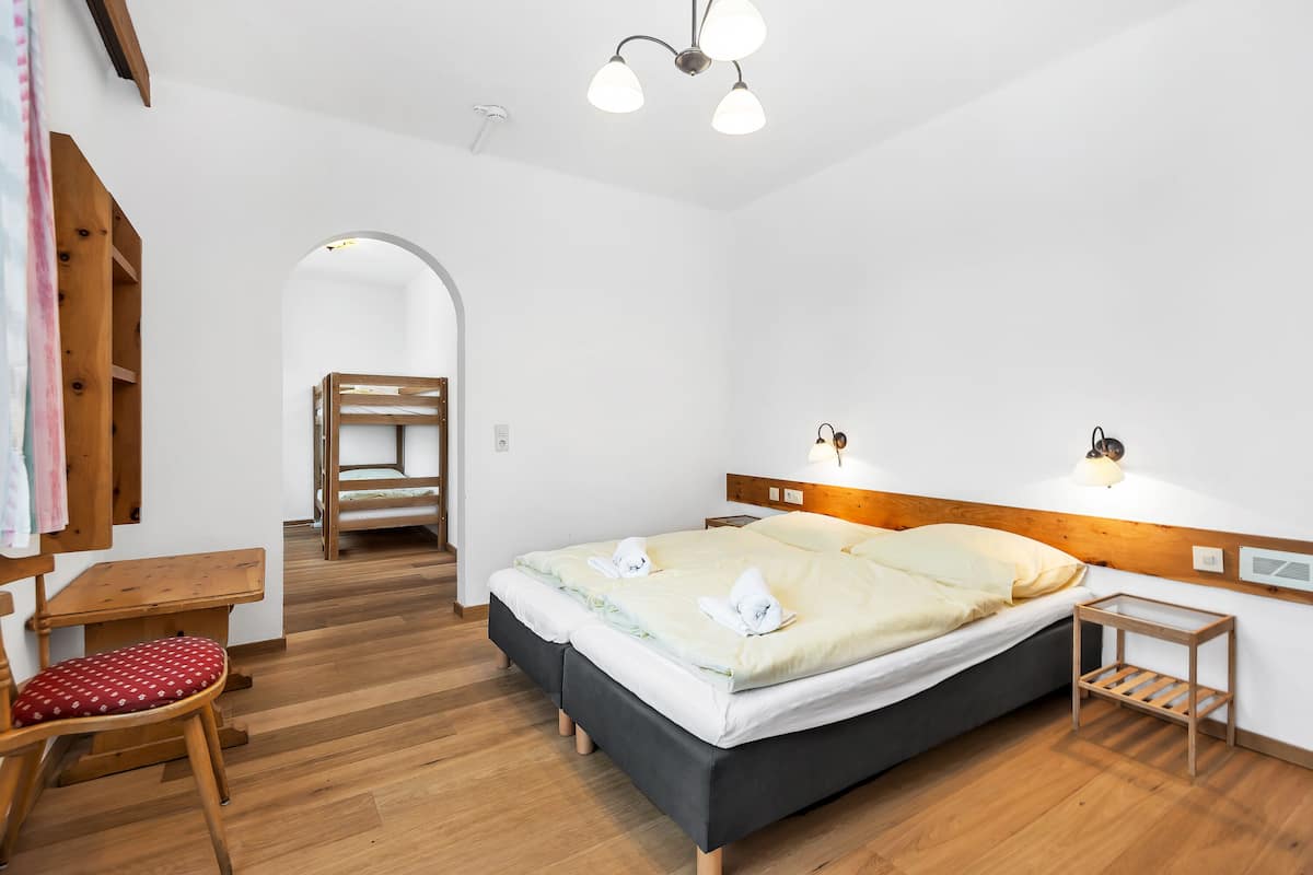 Een slaapkamer met een houten bed, een bureau, een stoel en een klein tafeltje.