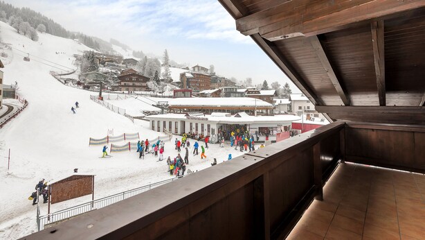 Ein Skigebiet mit einem Holzhaus, einer Seilbahn und einer schneebedeckten Piste.