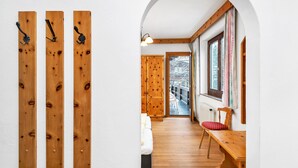 Ein Holzflur mit einer Bank und einem Tisch, einer Holztür und einem Fenster mit Vorhängen.