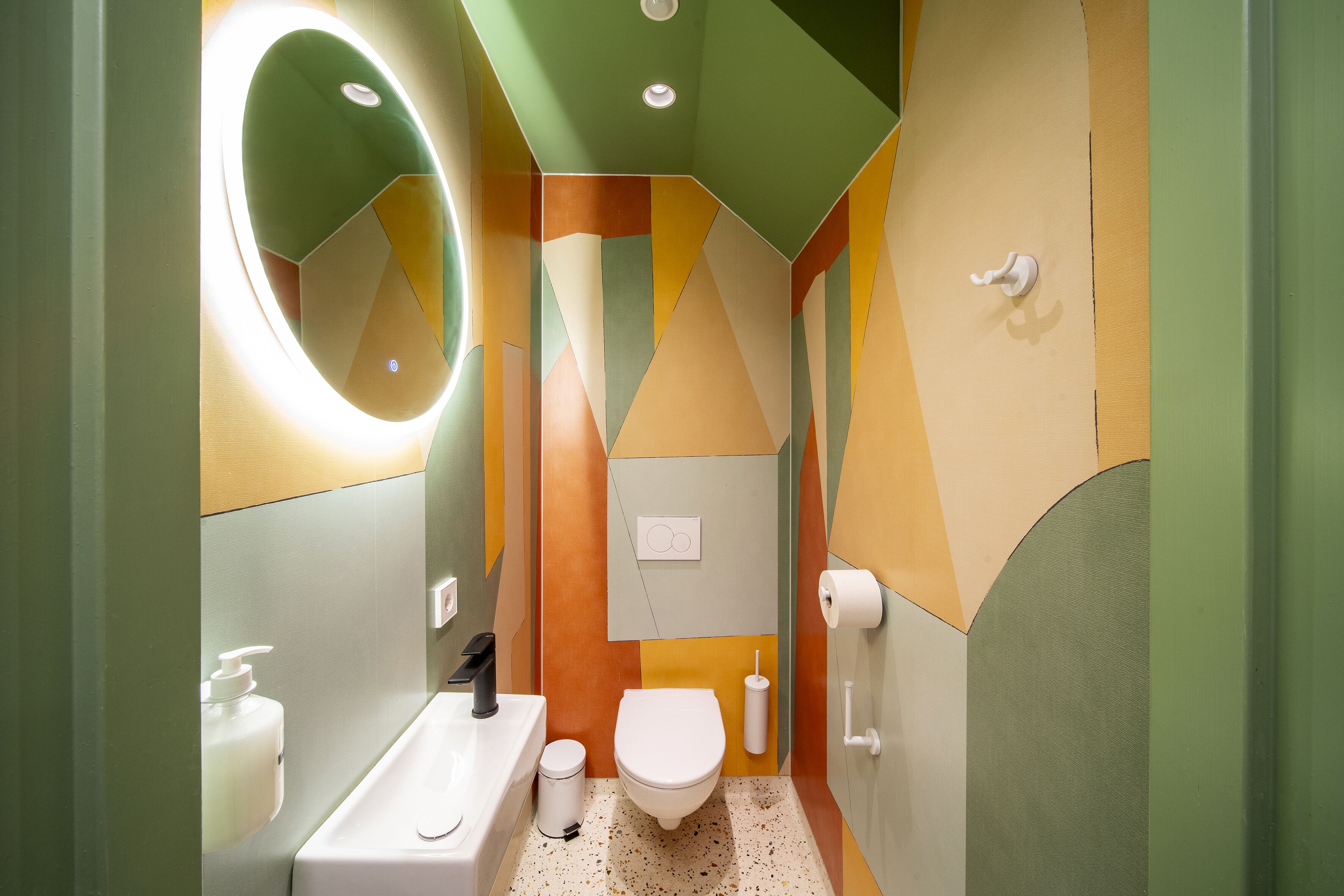 Un baño con diseño moderno, que incluye inodoro, lavamanos y espejo.