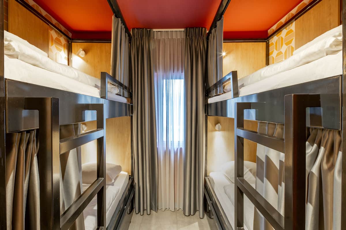 A bunk bed room with curtains, a window, and a wooden wall.