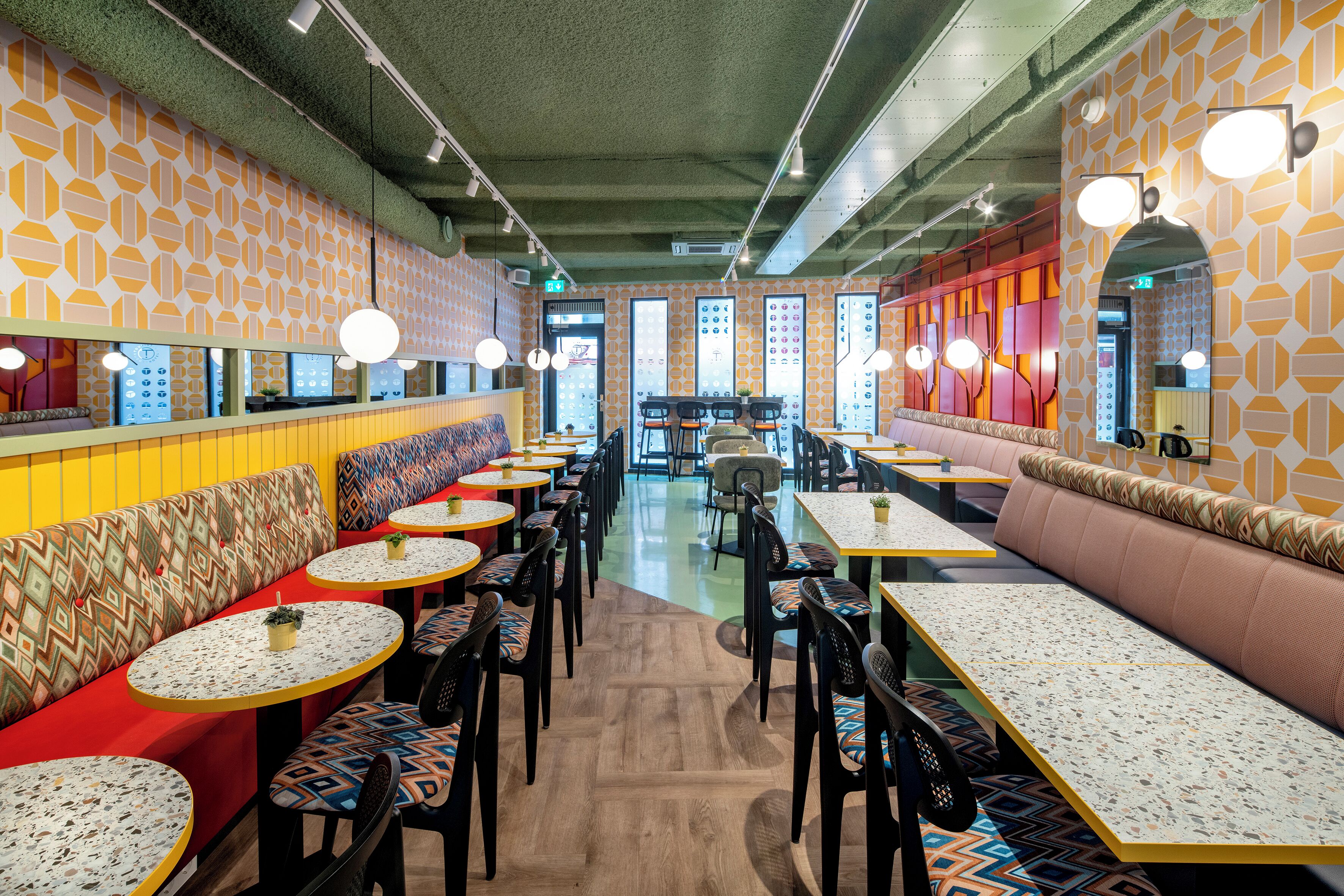 A restaurant with booths and tables, patterned walls, and a central walkway.