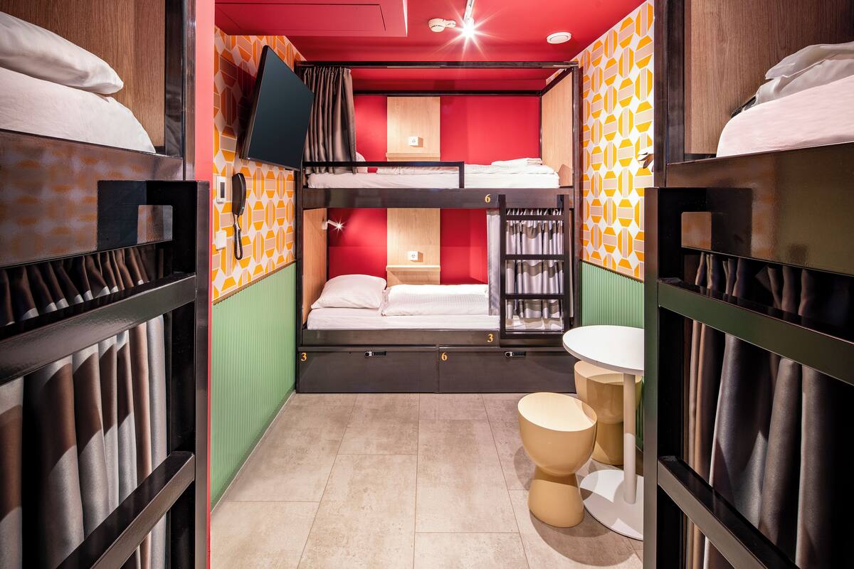 A compact hotel room with bunk beds, a small bathroom, and a green wall.