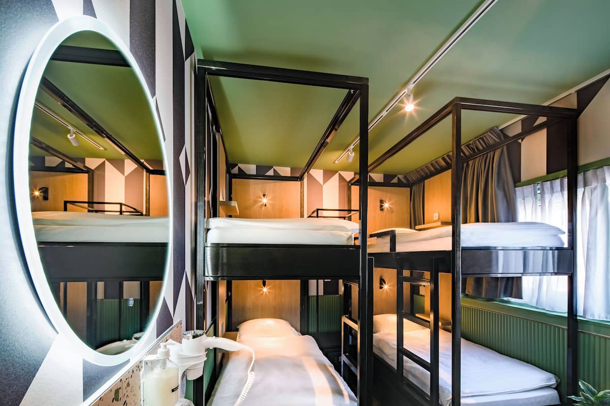 A bunk bed room with a mirror, a sink, and a window with curtains.