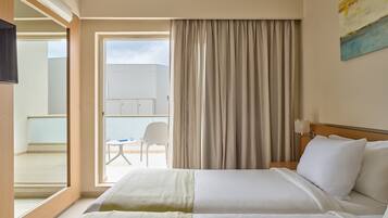 A hotel room with a bed, a chair, a window with curtains, and a view of the outside.