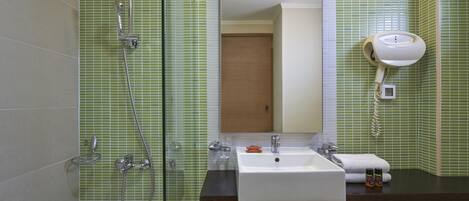 Un baño con bañera, ducha, lavamanos y secador de pelo fijado a la pared.