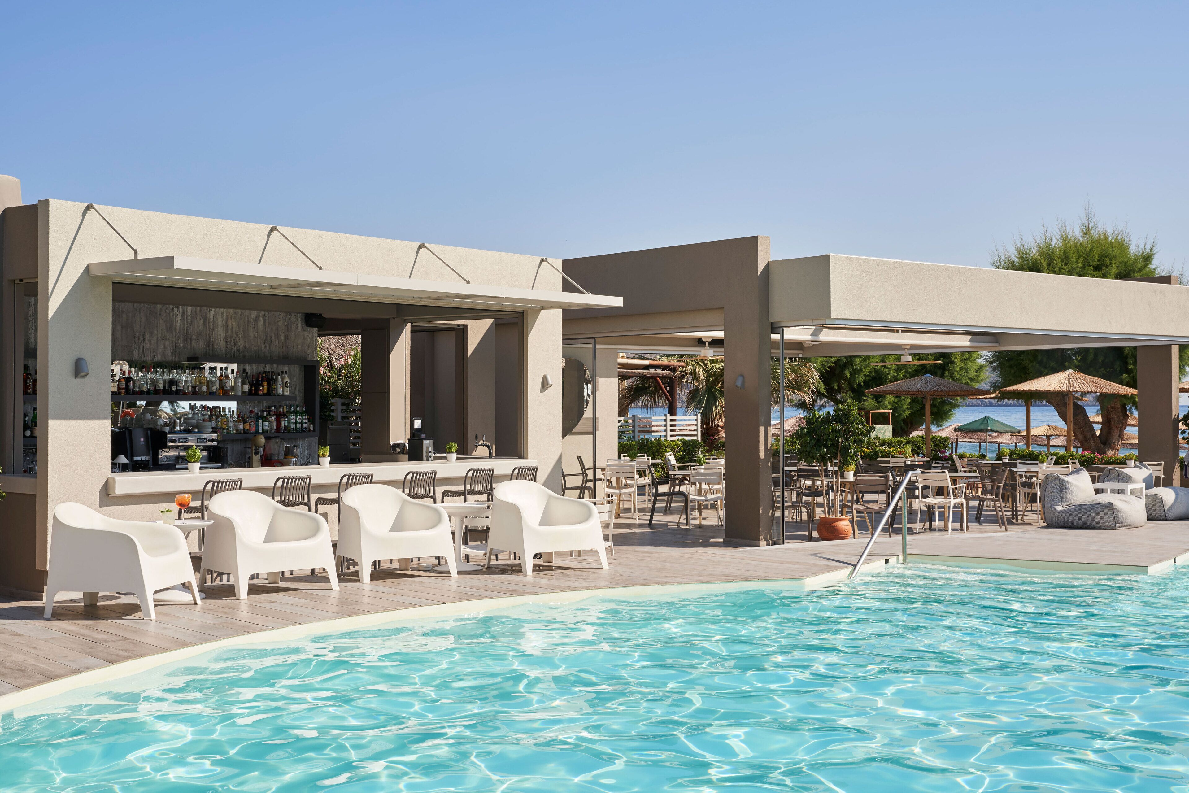 A poolside area with a bar, white lounge chairs, and outdoor seating.