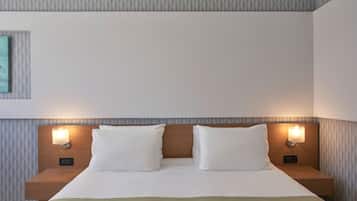 Une chambre d’hôtel avec un lit bien fait, deux tables de chevet avec des lampes et un mur orné d’un motif.