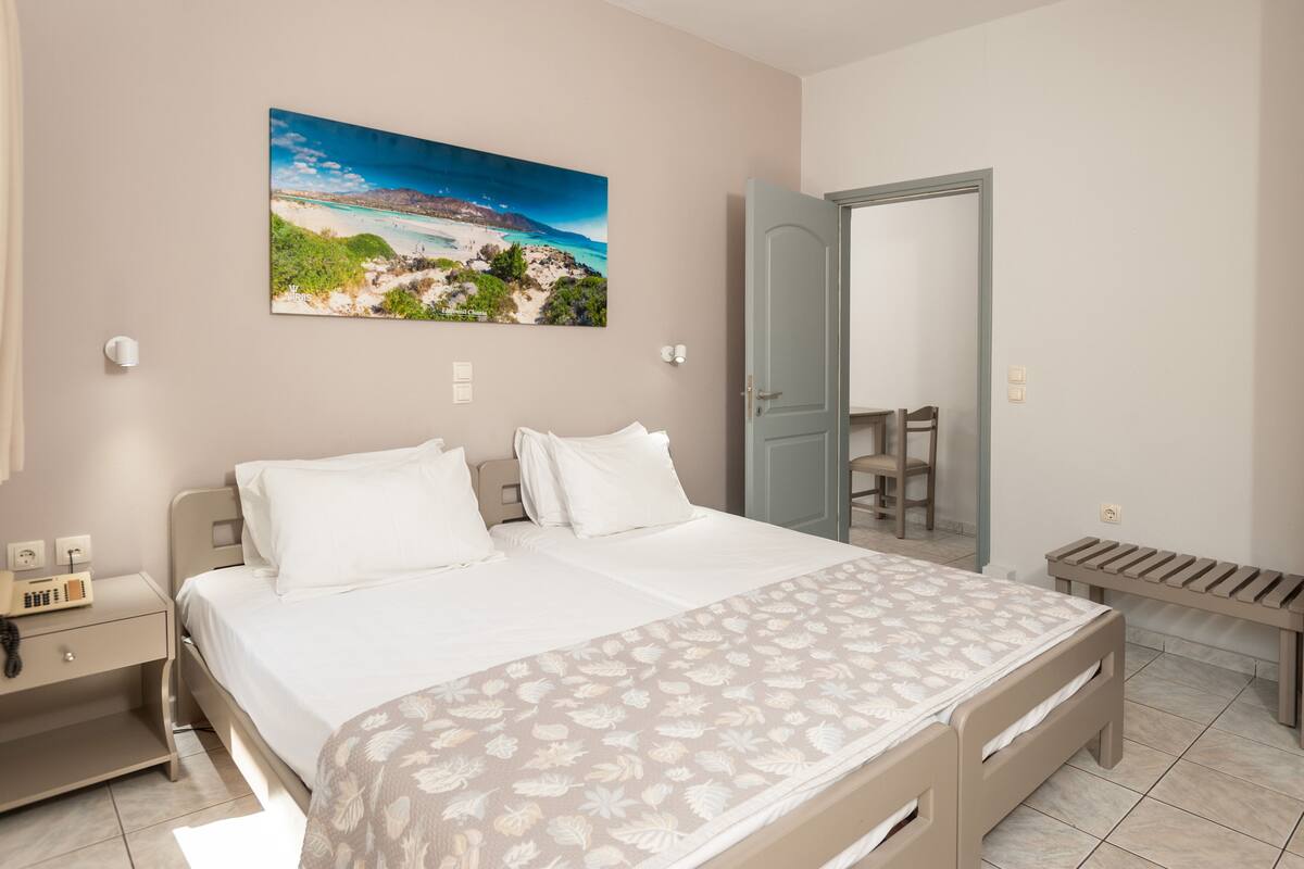 A bedroom with a large bed, a bedside table with a lamp, a chair, and a bench.