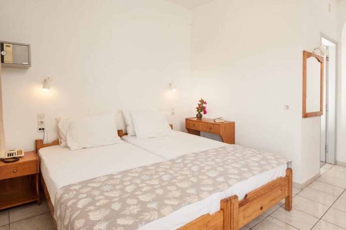 A bedroom with a double bed, bedside tables, a nightstand, a mirror, and a wall-mounted light fixture.