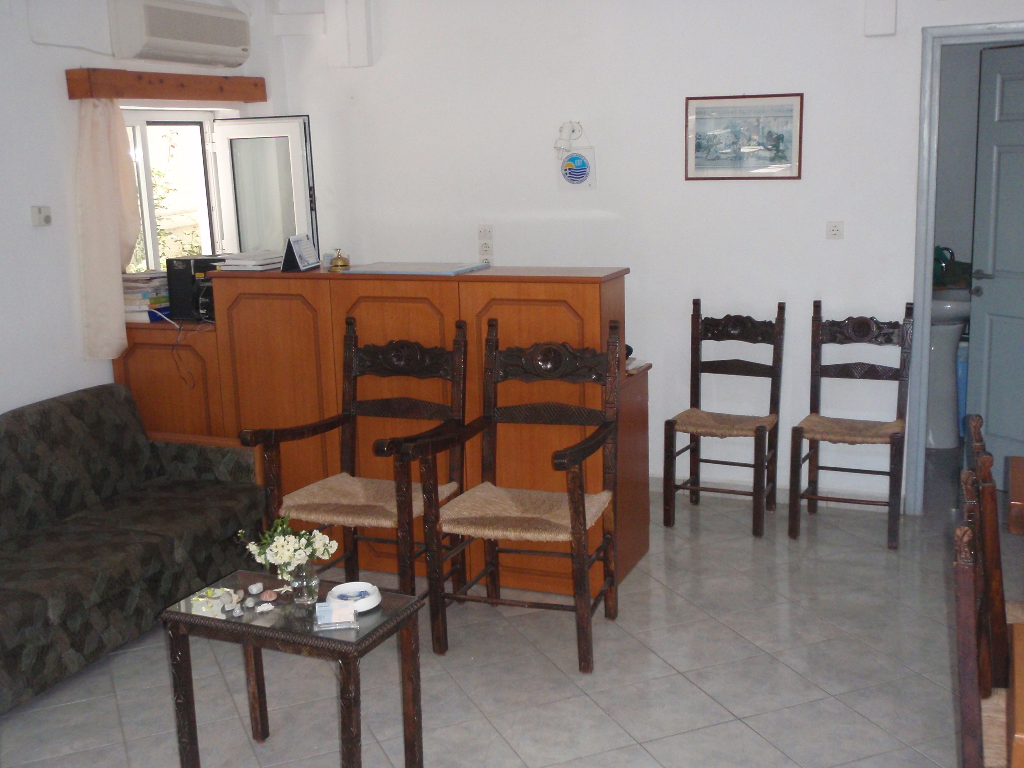 Un salon comprenant un canapé, deux fauteuils en bois, une petite table avec un vase et un meuble en bois.