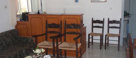 Un salon comprenant un canapé, deux fauteuils en bois, une petite table avec un vase et un meuble en bois.
