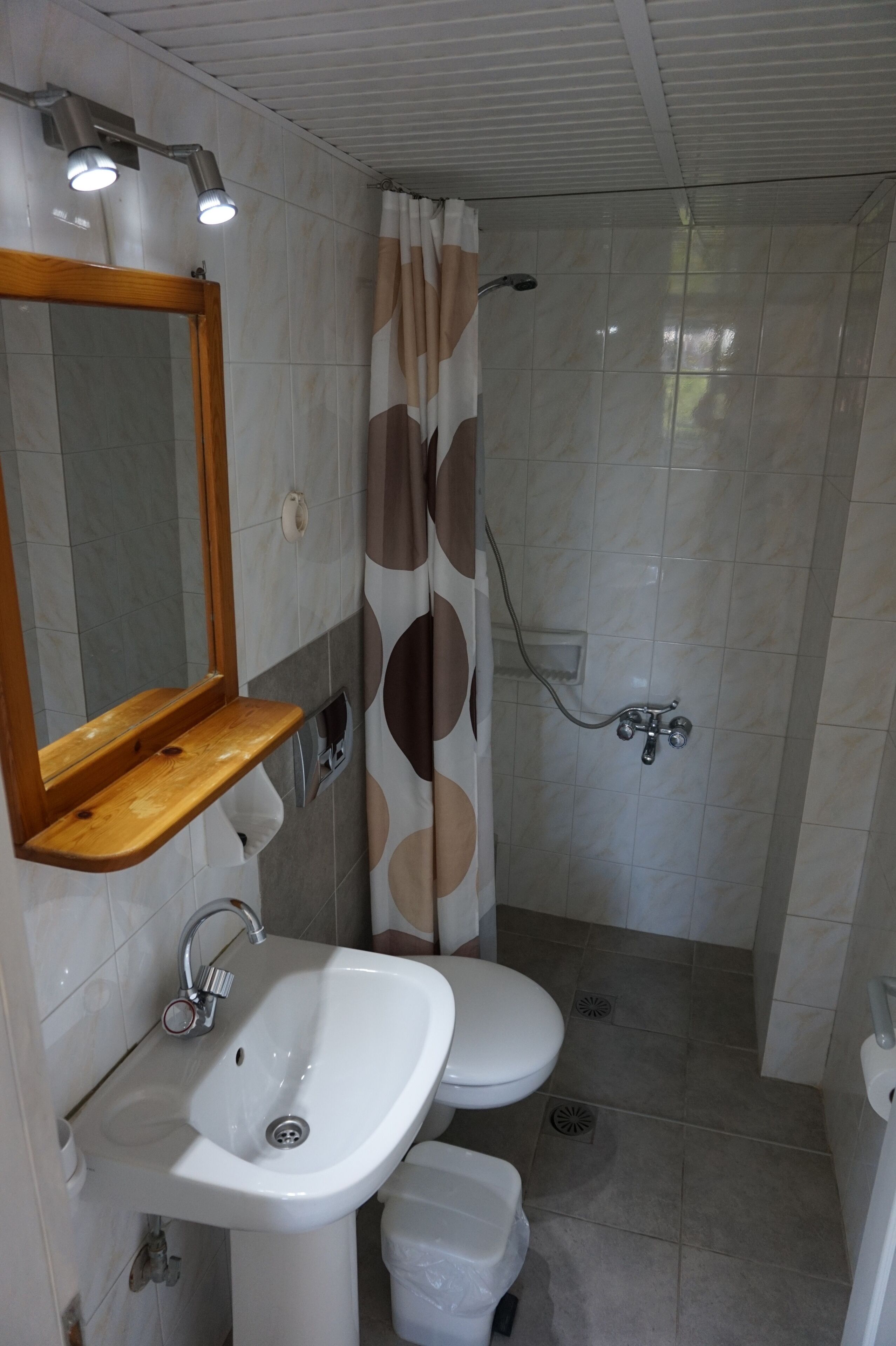 A bathroom with a sink, mirror, toilet, shower, and towel rack.