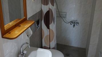 A bathroom with a sink, mirror, toilet, shower, and towel rack.