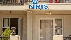 A hotel entrance with a balcony, a door, and a logo. - Niriis Hotel (Chania)