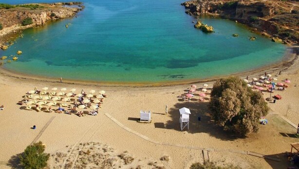 A beach with clear turquoise waters, sandy shore, and umbrellas. - Niriis Hotel (Chania)