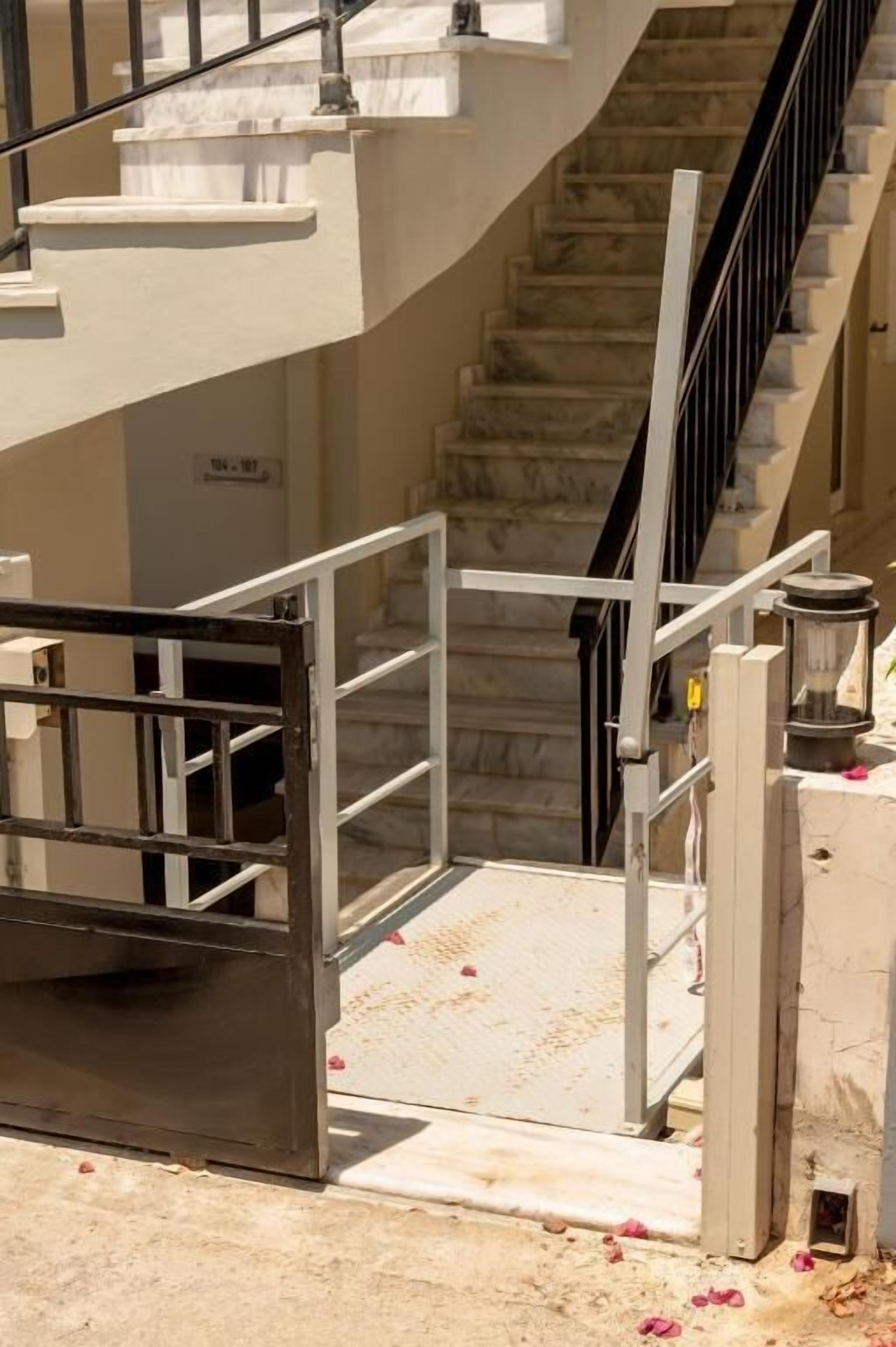 A spiral staircase with a metal railing, marble steps, and a door at the bottom.