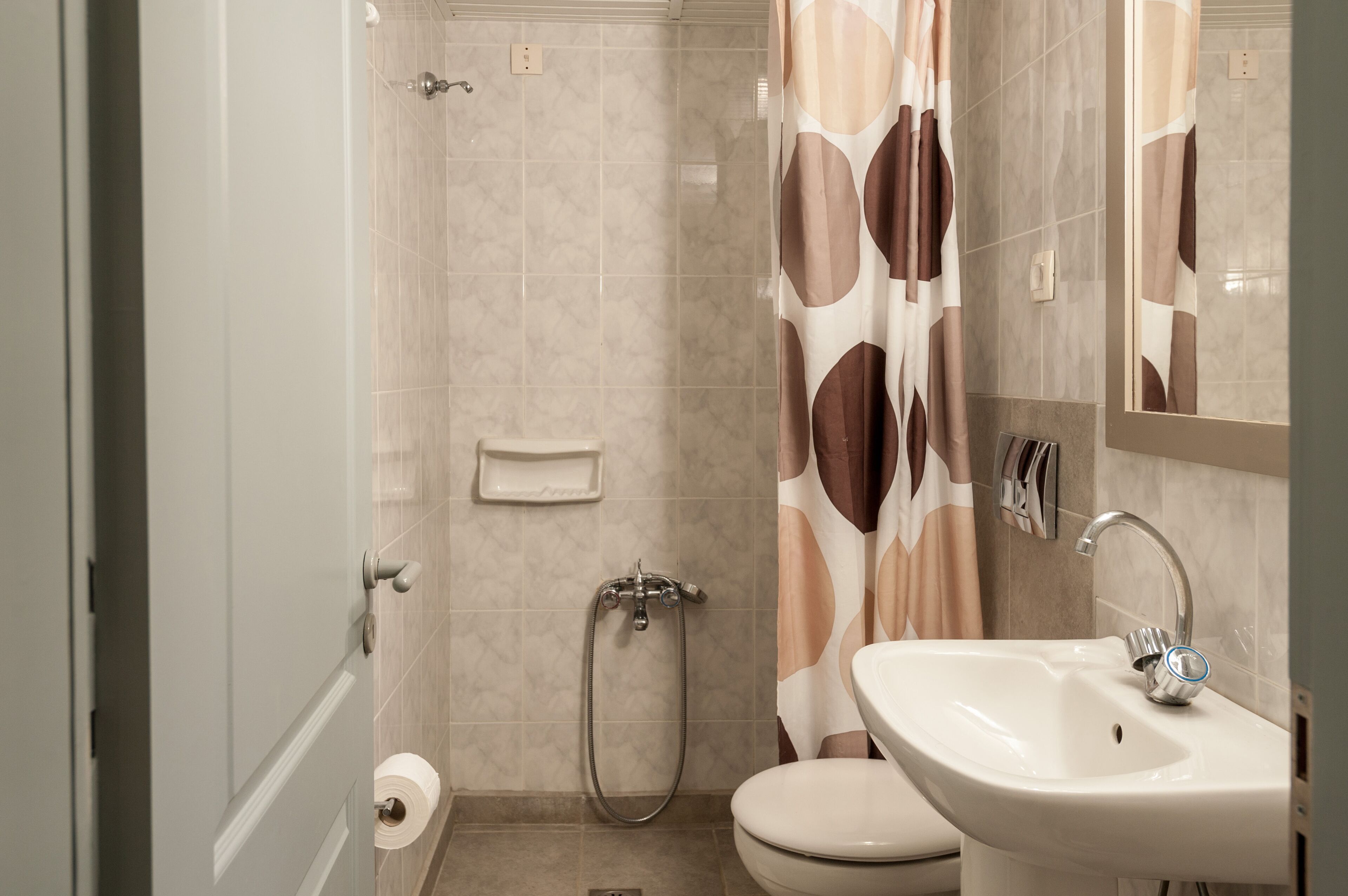 A bathroom with a toilet, sink, shower, and a towel rack.