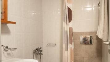 Une salle de bain équipée d’une douche, de toilettes, d’un lavabo et d’un porte-serviettes.