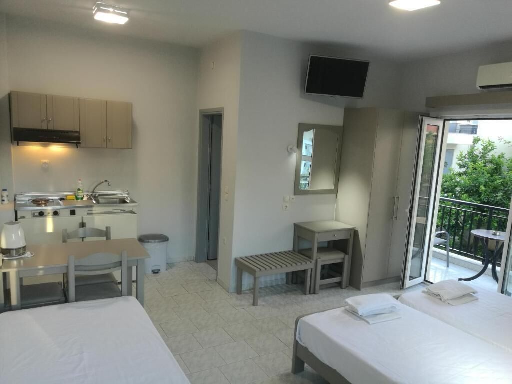 Una camera d'albergo con angolo cottura, un letto, un piccolo tavolo, una sedia, una TV e un balcone con vista.