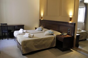 Habitación de hotel con dos camas, un escritorio y una silla.