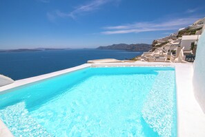 A clear blue pool with a view of the sea and white buildings. - Alexander's Suites (Santorini)