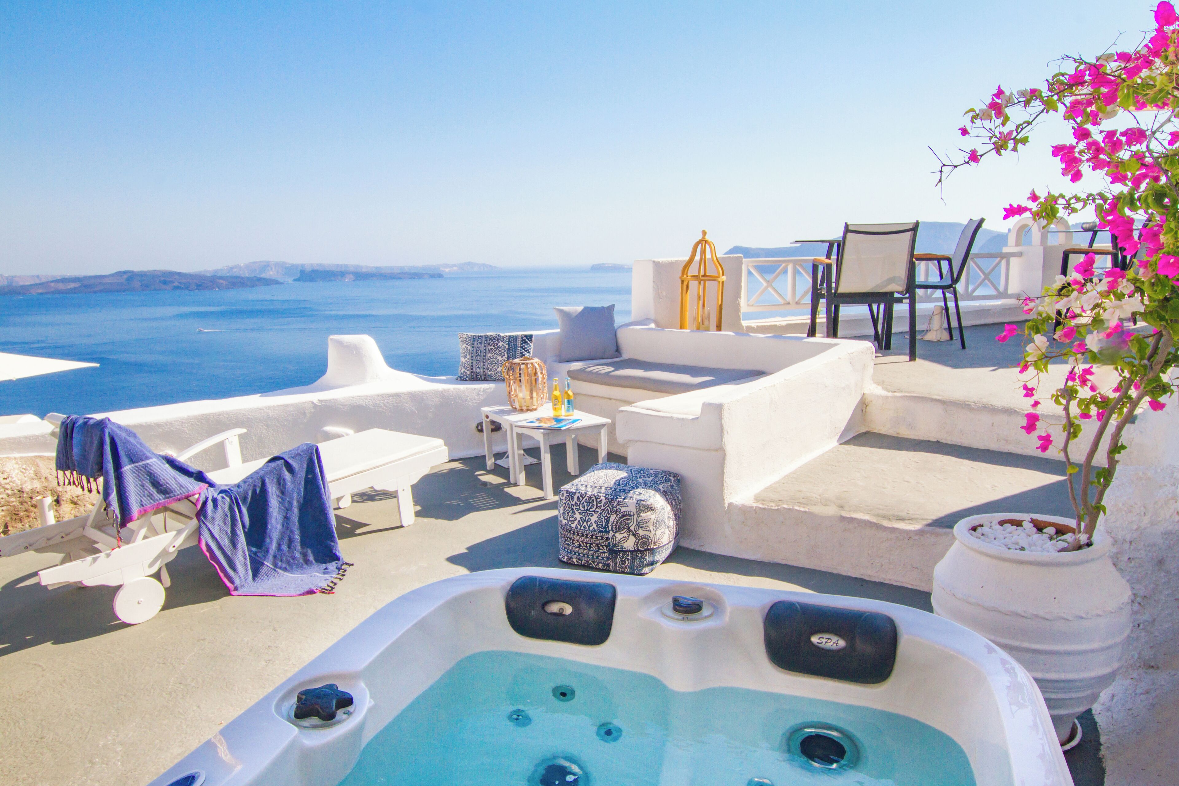 A rooftop terrace with a hot tub, lounge chairs, and a view of the sea.