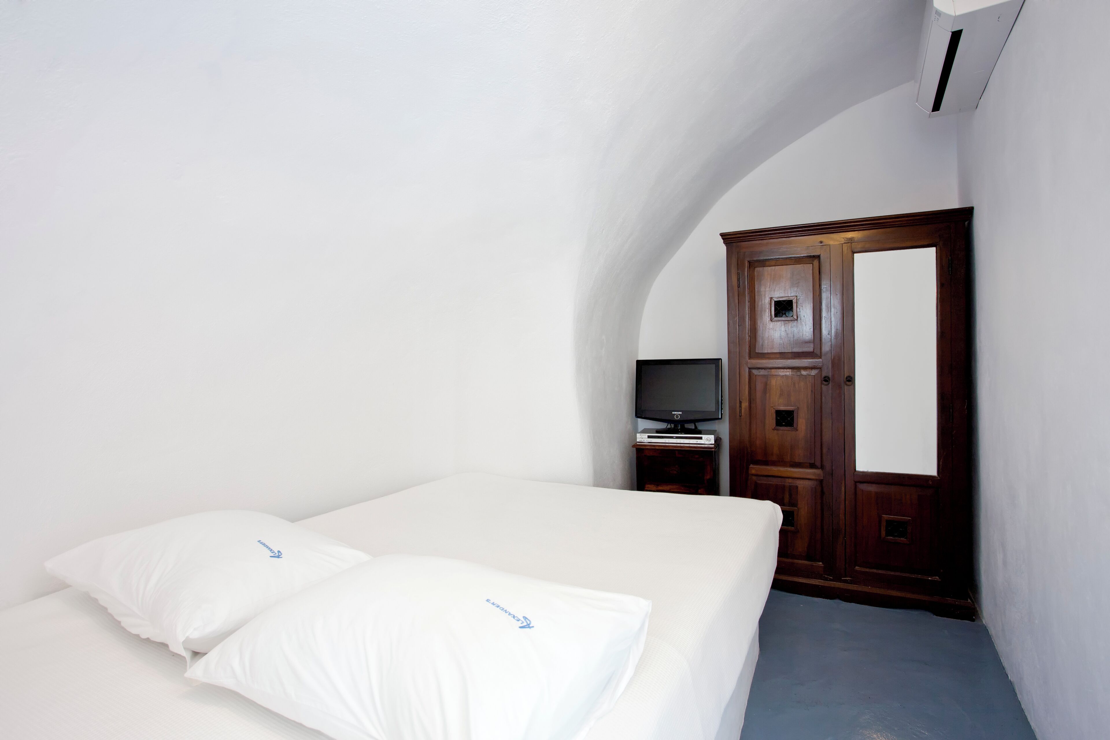Une chambre à coucher avec un lit, une télévision et une armoire.