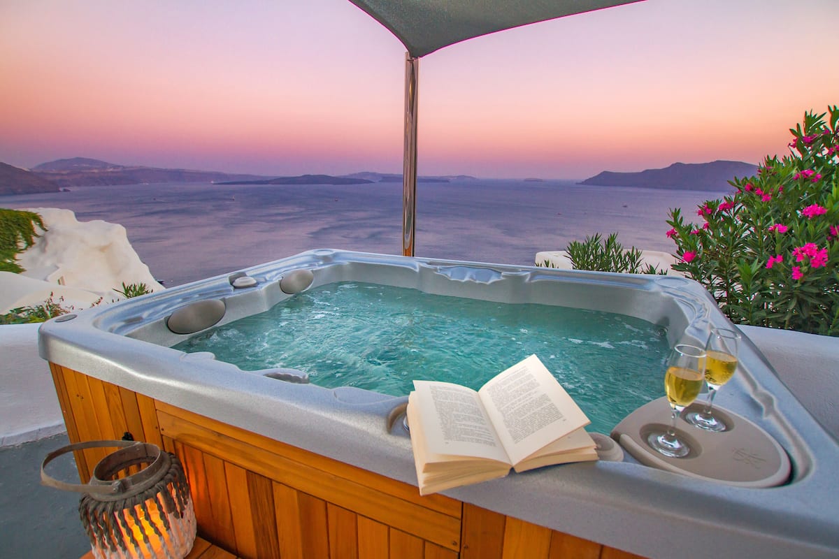 A hot tub with a book and glasses, overlooking a scenic view.