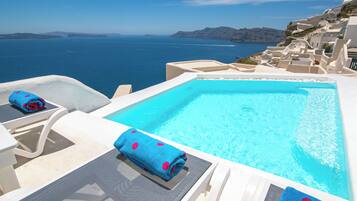 A pool area with a view of the sea and white buildings.