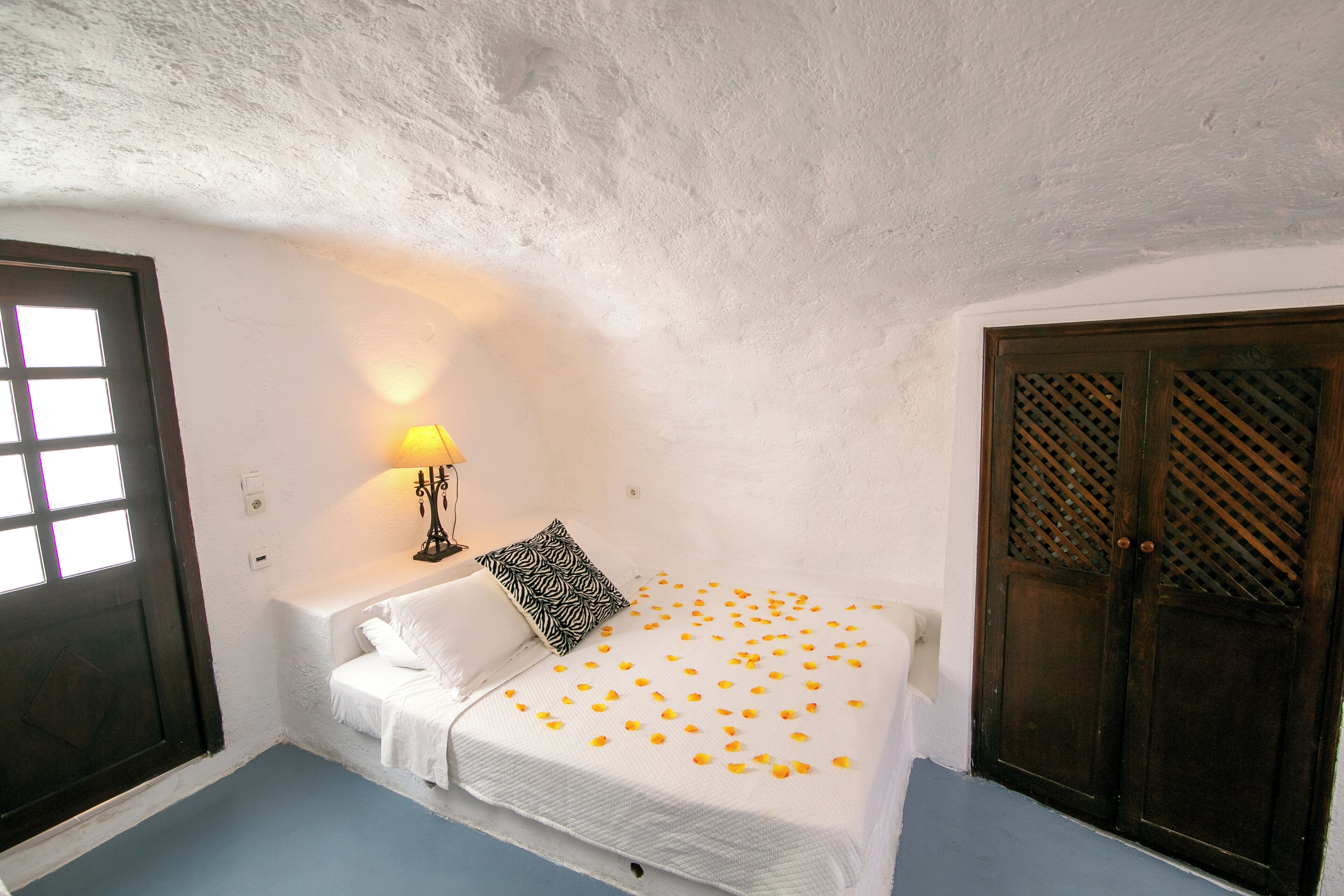 A bedroom with a bed, a nightstand, a lamp, and a door.