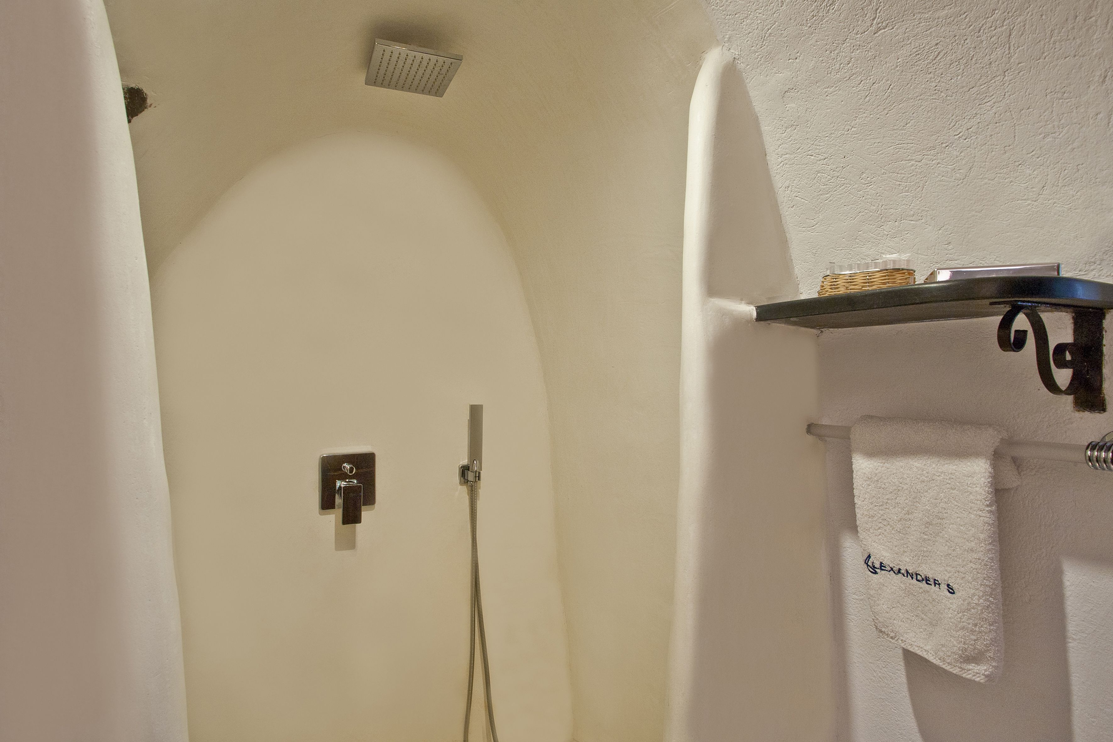 A bathroom with a shower, a towel rack with a towel, and a shelf with a basket.