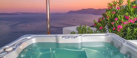 A hot tub with a view of the sea and mountains.