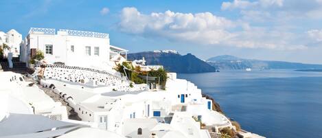 A coastal village with white buildings, a clear blue sky, and a view of the sea.