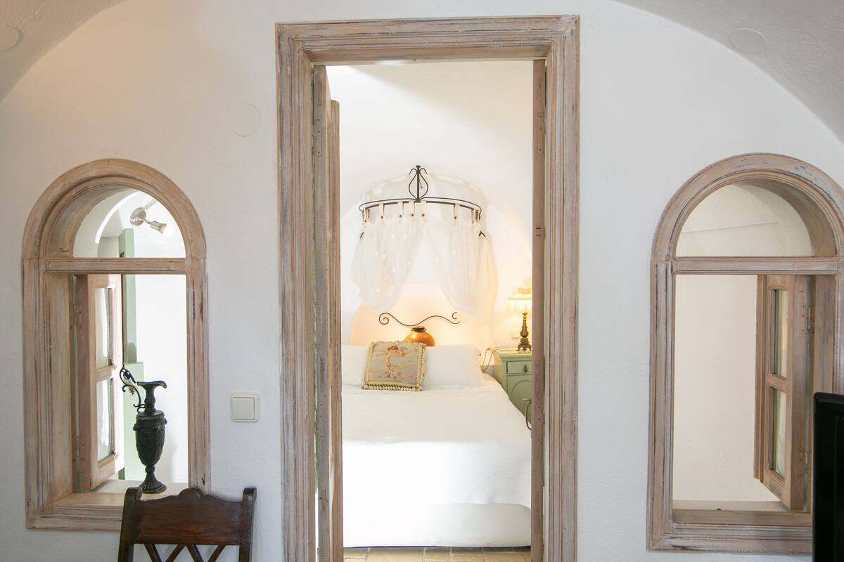 A bedroom with a bed, a nightstand, a lamp, and a chair.