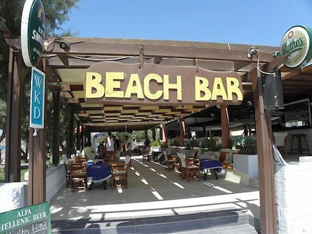 A beach bar with outdoor seating and a covered area.