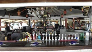 Un espace bar avec un comptoir, des luminaires suspendus et diverses bouteilles.