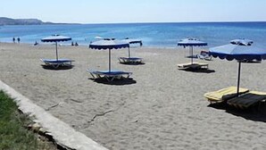 Une plage avec plusieurs parasols et des chaises longues.