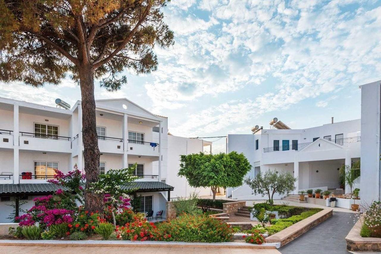 A multi-story building with balconies, surrounded by landscaped gardens and trees.