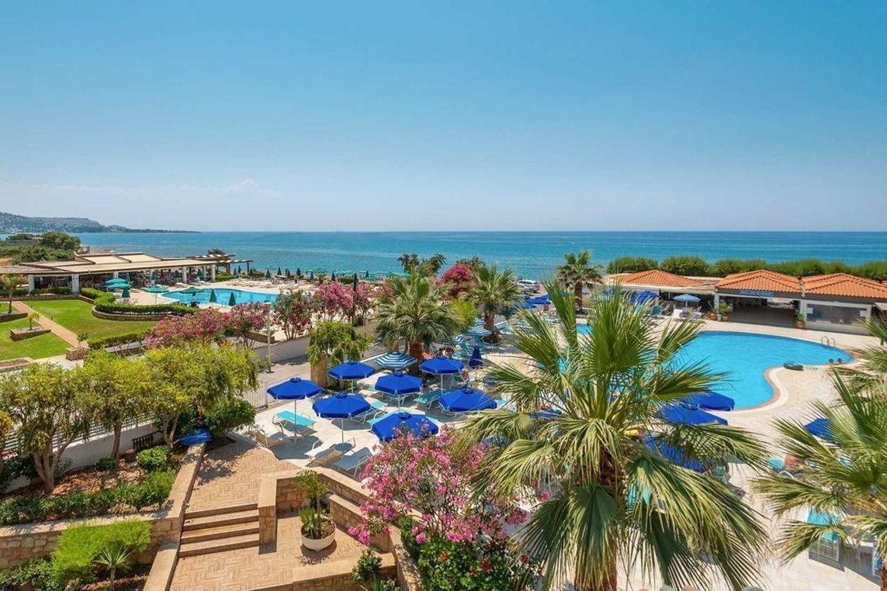 A resort with a swimming pool, lounge chairs, and palm trees.