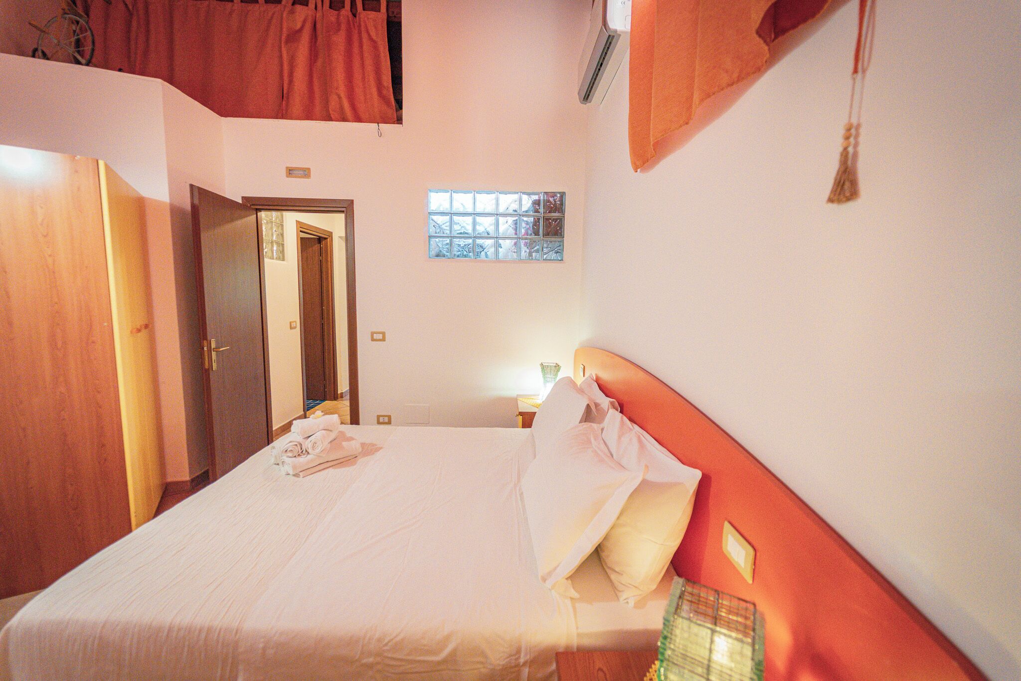 A bedroom with a bed, a window, and a door.