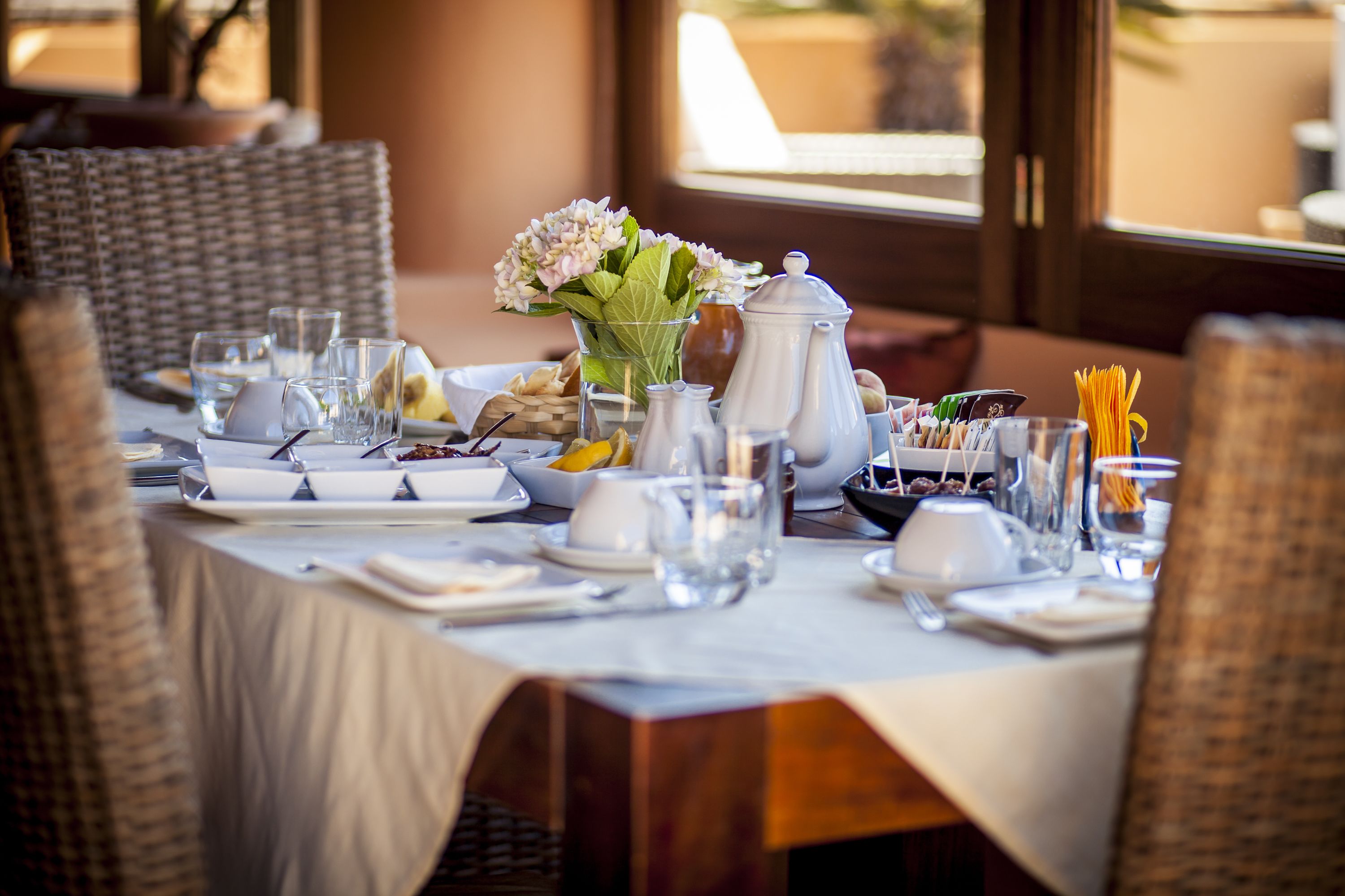 A dining table set with plates, glasses, a vase of flowers, and a pitcher.