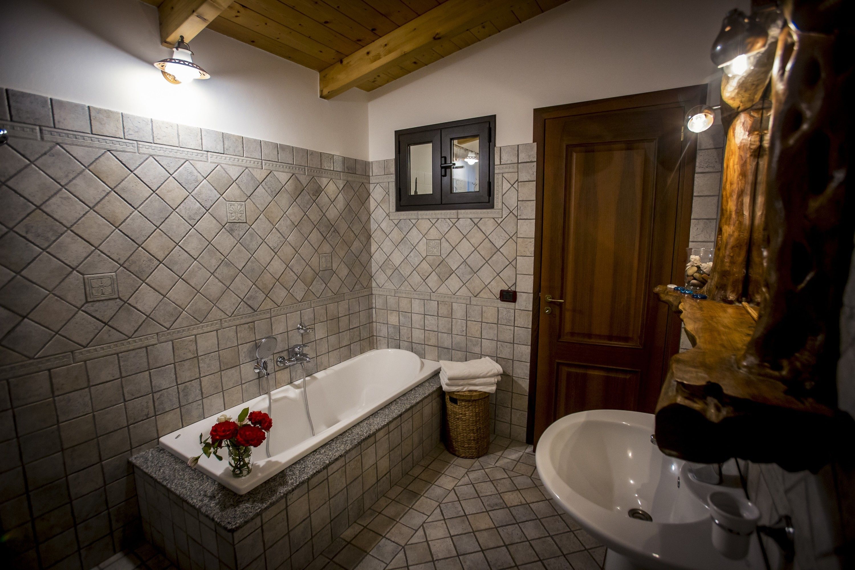 A bathroom with a freestanding bathtub, a sink, and a wooden door.