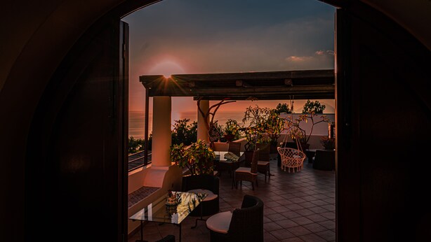 An outdoor patio area with a pergola, seating, and potted plants. - Al Belvedere Salina (Leni)