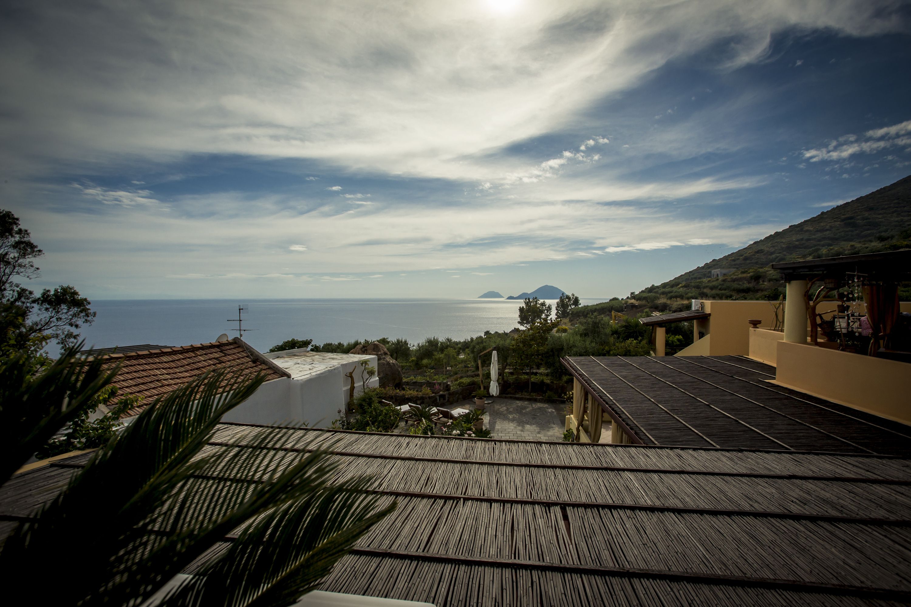 A coastal view with a wooden deck, a white building, and a mountain in the background.